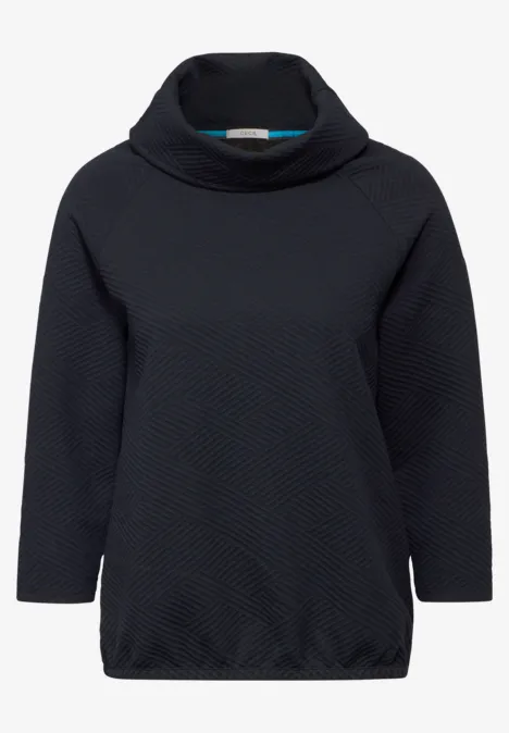 Dunkler Pullover mit Stehkragen und Muster.
